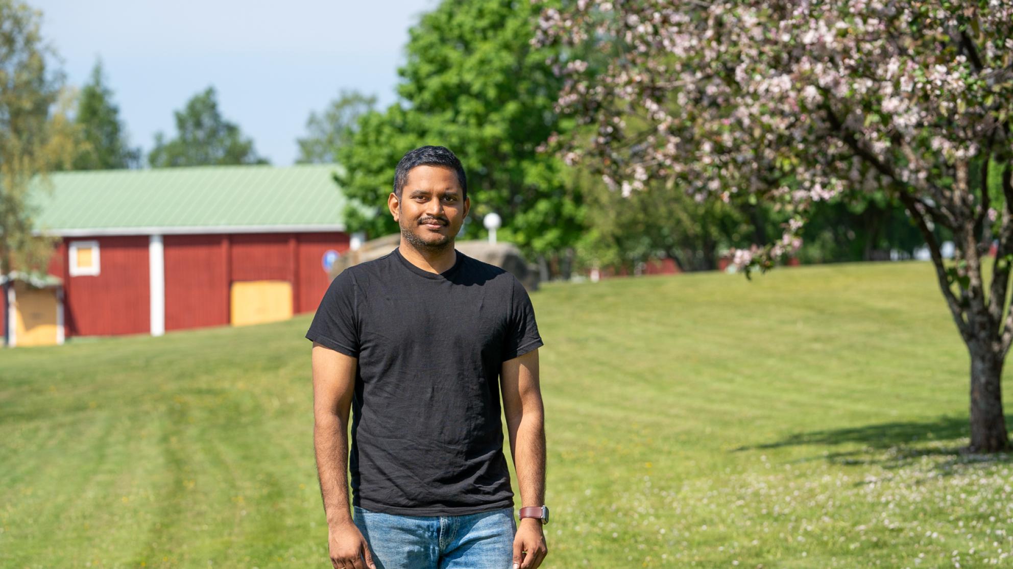 Alumnus Raja Marthala visiting the University of Vaasa campus, green grass and a blossoming tree on the background.