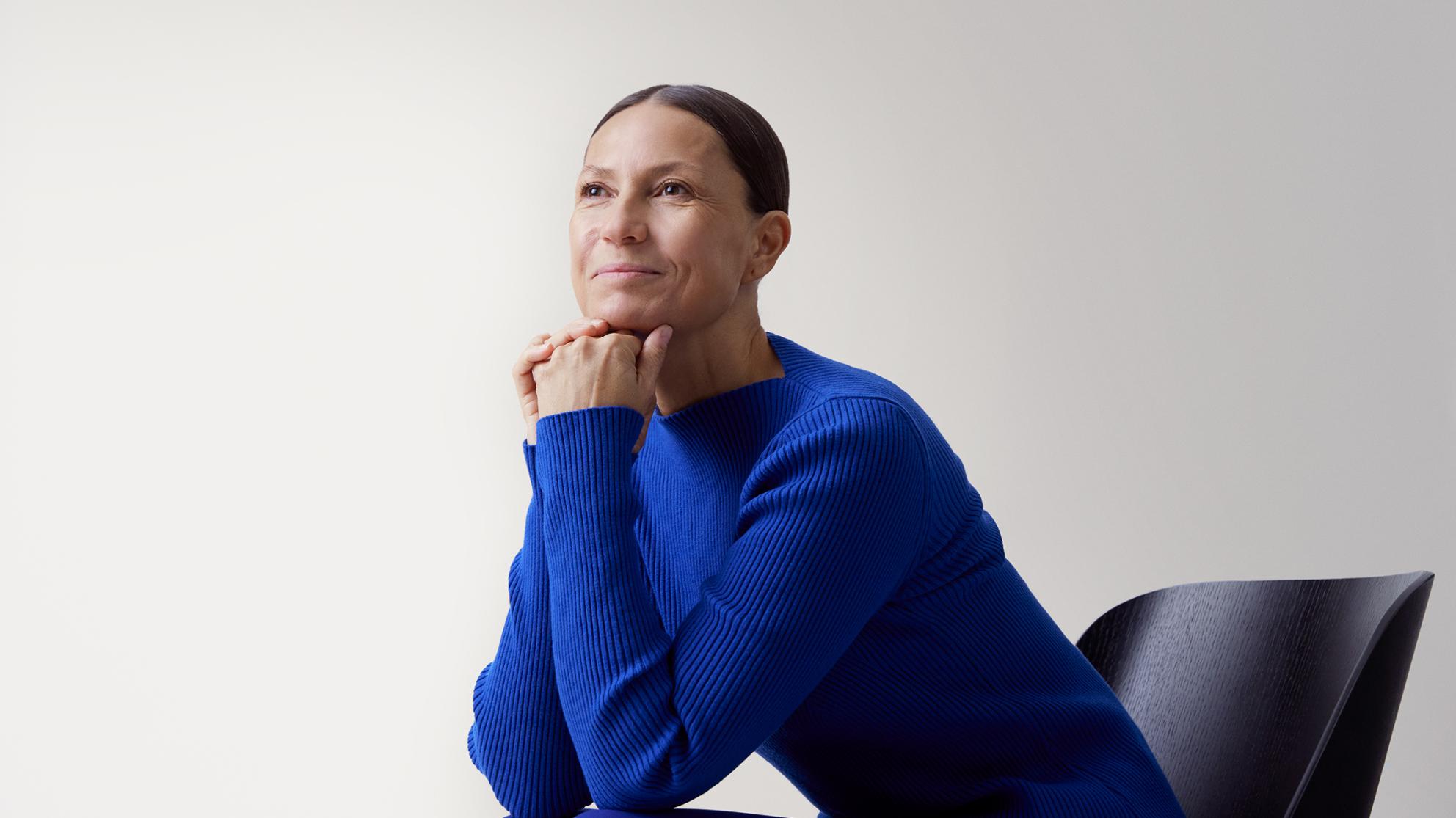 Opin.fi-palvelu. Nainen sinisessä paidassa nojaa pöytään ja katsoo kaukaisuuteen.