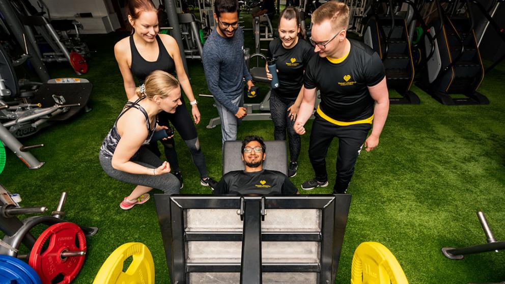 Athlete doing leg press and friends cheering them on