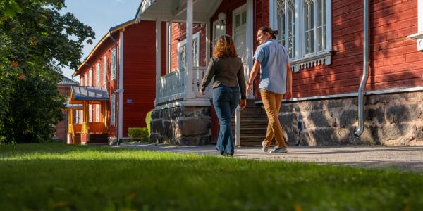 Kaksi ihmistä kävelemässä Vaasan yliopiston Puuvilla-talon edustalla.