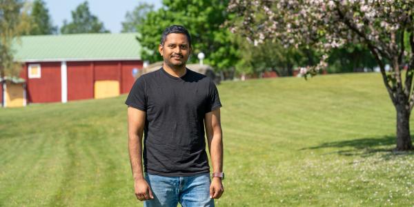 Alumnus Raja Marthala visiting the University of Vaasa campus, green grass and a blossoming tree on the background.